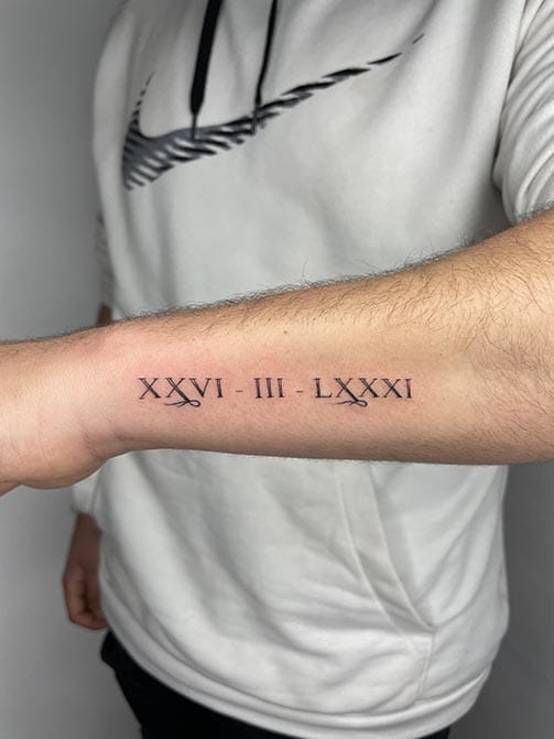 Tatuaje para hombre con significado de familia, fecha con números romanos en el antebrazo