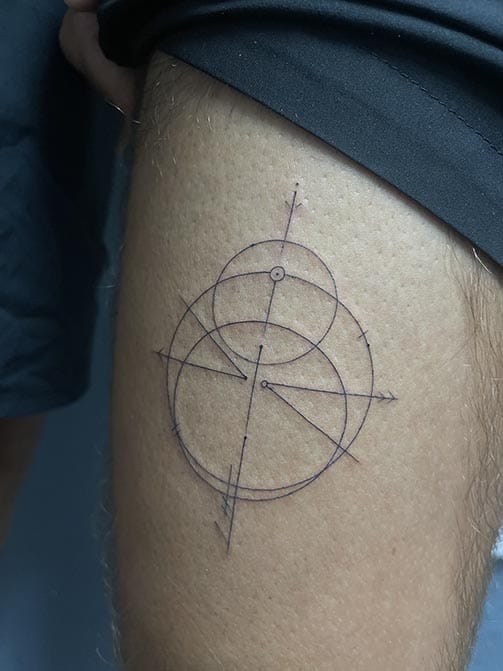 Tatuaje pequeño para hombre de una brújula minimalista en el muslo muslo