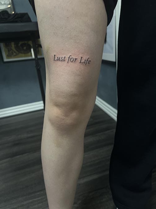 Tatuaje para hombre pequeño de una frase en ingles en el muslo