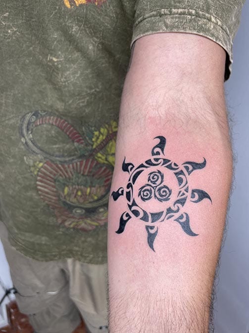 Tatuaje pequeño para hombre de un sol estilo tribal en el brazo