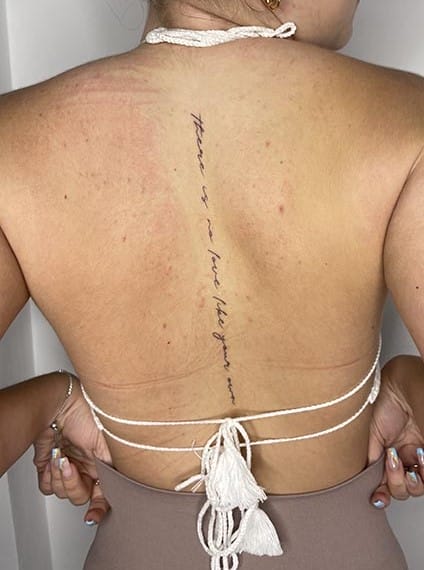 Tatuaje en la columna para mujer de una frase en la espalda
