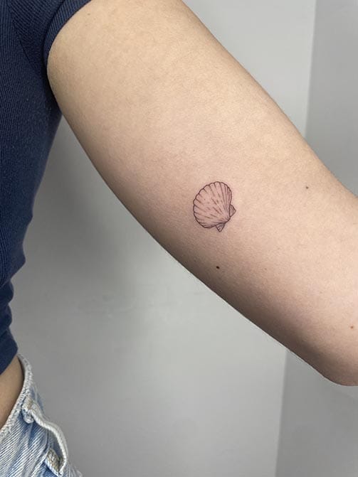 Tatuaje minimalista femenino de una concha pequeña para mujer en el brazo