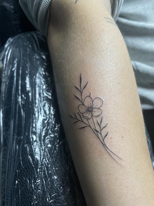Tatuaje minimalista femenino de una flor de almendro pequeña para mujer en el antebrazo