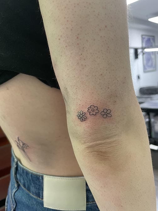 Tatuaje minimalista femenino de flores pequeñas para mujer en el antebrazo