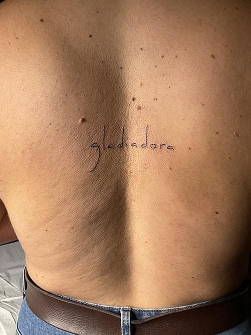 Tatuaje minimalista femenino de una palabra pequeña para mujer en la espalda