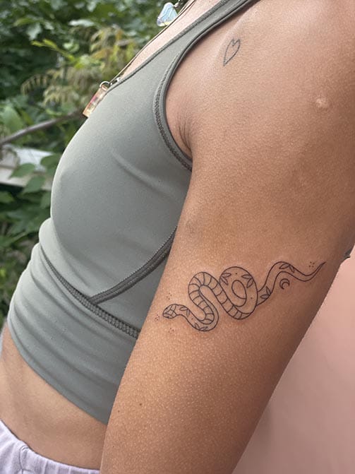 Tatuaje minimalista femenino de una serpiente pequeña para mujer en el brazo