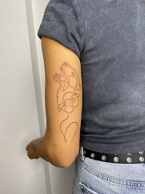 Tatuaje minimalista femenino de una mujer y un tigre entrelazados en el brazo