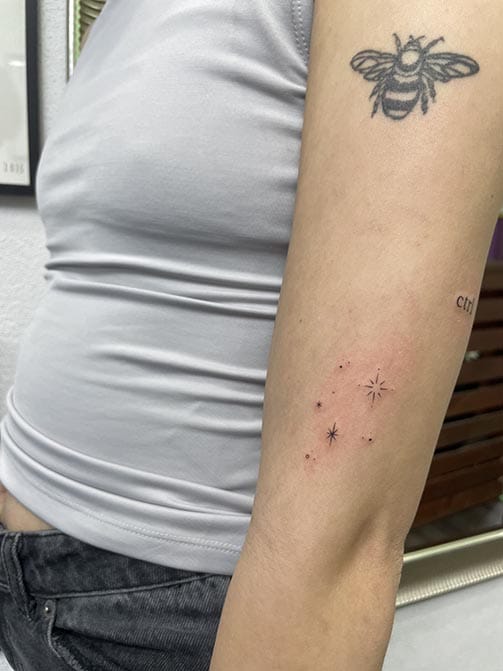 Tatuaje estilo fine line de estrellas en el brazo