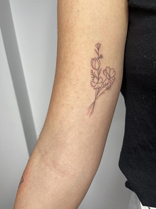 Tatuaje estilo fine line de un ramo de flores en el brazo