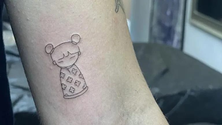 Tatuaje estilo fine line de una muñeca en el brazo