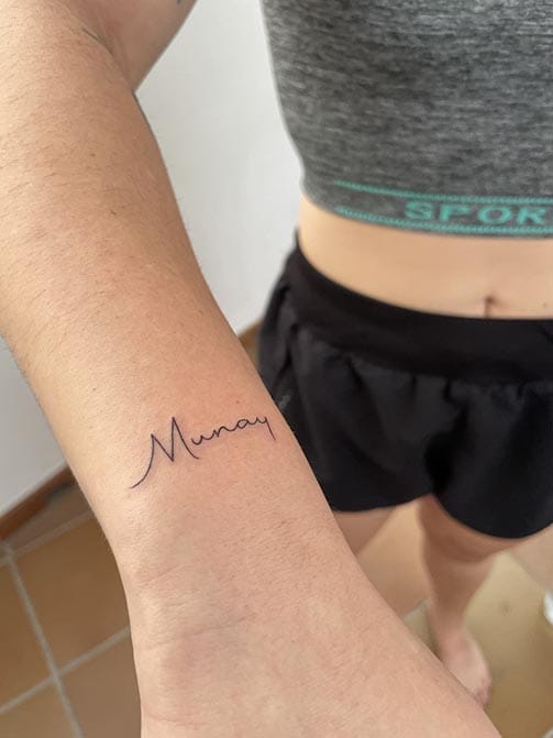 Tatuaje estilo fine line de una palabra en la muñeca