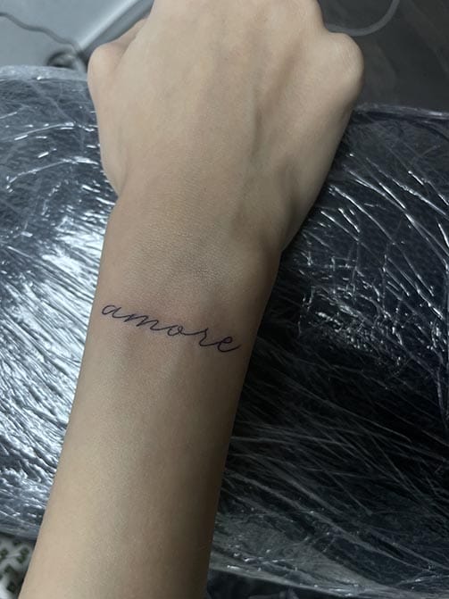 Tatuaje estilo fine line de una palabra en la muñeca