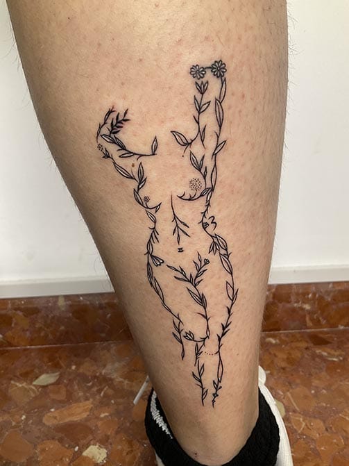 Tatuaje estilo fine line de la silueta del cuerpo de una mujer hecha de ramas y flores