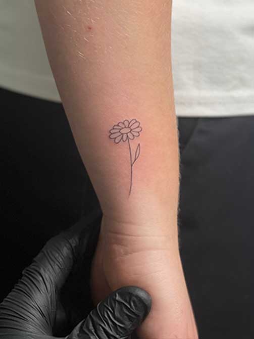 Tatuaje de flores con significado, margarita en el antebrazo
