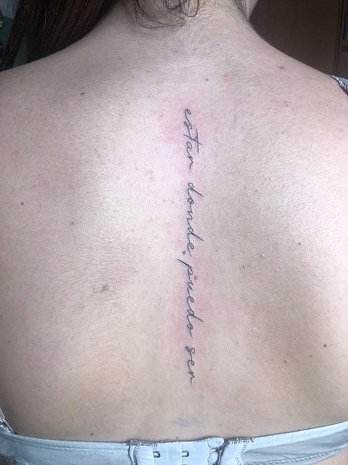 Tatuaje en la columna para mujer de una frase en la espalda