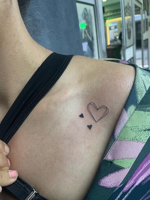 Tatuaje minimalista femenino de un corazón pequeño para mujer en el hombro