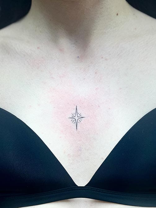 Tatuaje minimalista femenino de una estrella pequeña para mujer en el pecho