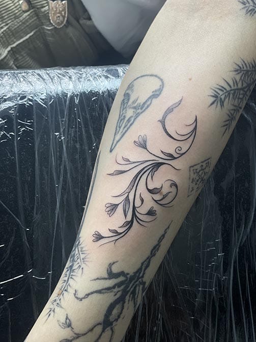 Tatuaje pequeño para mujer en el brazo de temática botánica de ramas