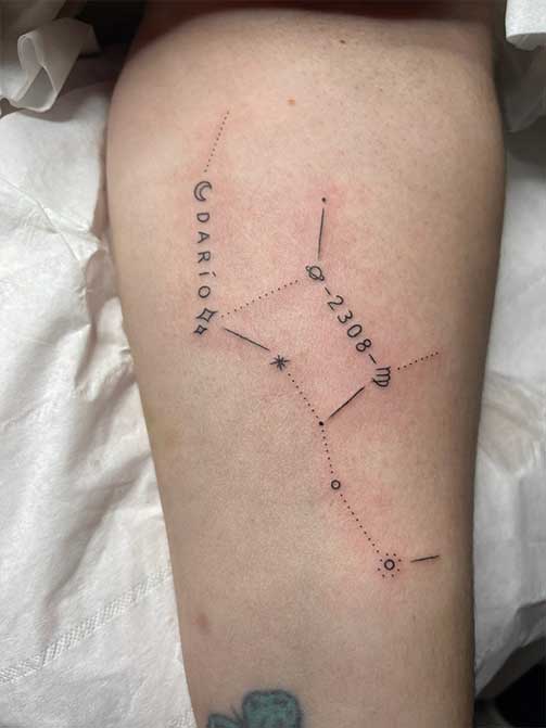 Tatuaje pequeño para mujer en el brazo de una constelación con nombre y fecha de nacimiento