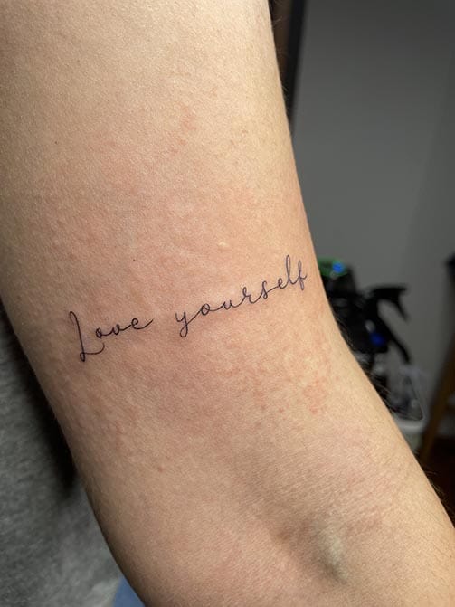 Tatuaje pequeño para mujer en el brazo de una frase en ingles