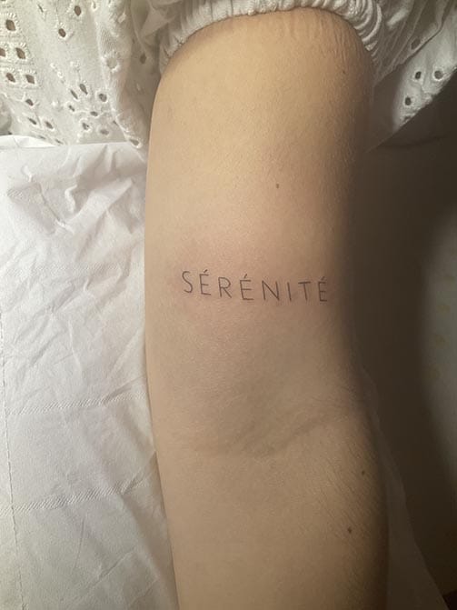Tatuaje pequeño con significado para mujer de una palabra en el brazo