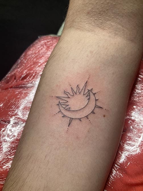 Tatuaje pequeño con significado para mujer de un sol y una luna en el antebrazo